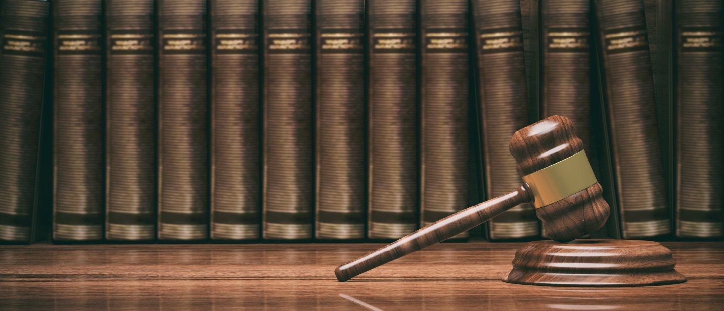 法官的小木槌，搁在摆满棕色书籍的书架上.